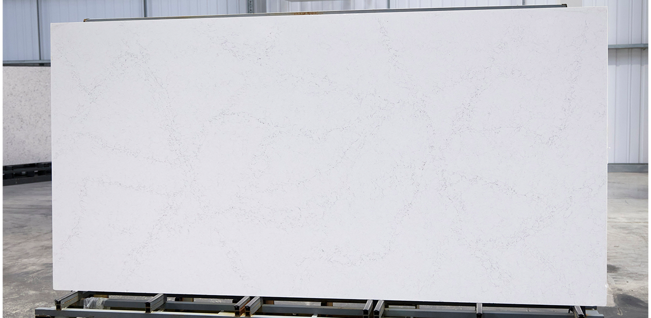 Full Slab view of Statuario Bianco Quartz with a white background scattered with grey veining.