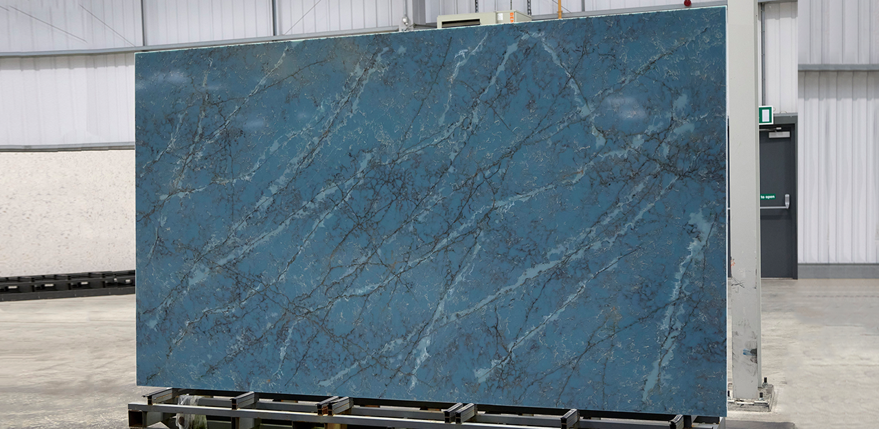 Slab view of Cristallo Azure Quartz with a azure surface and brown, and light blue veining.