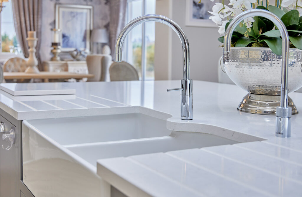 A close-up of a white quartz worktop featuring high-quality materials and a sleek chrome tap. a dreamy kitchen with modern engineered surfaces, White Water quartz.