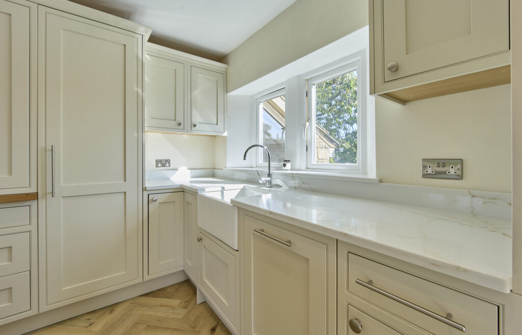 A creamy white kitchen with a silica free statuario oro surface that has a creamy white base and golden-brown veins.