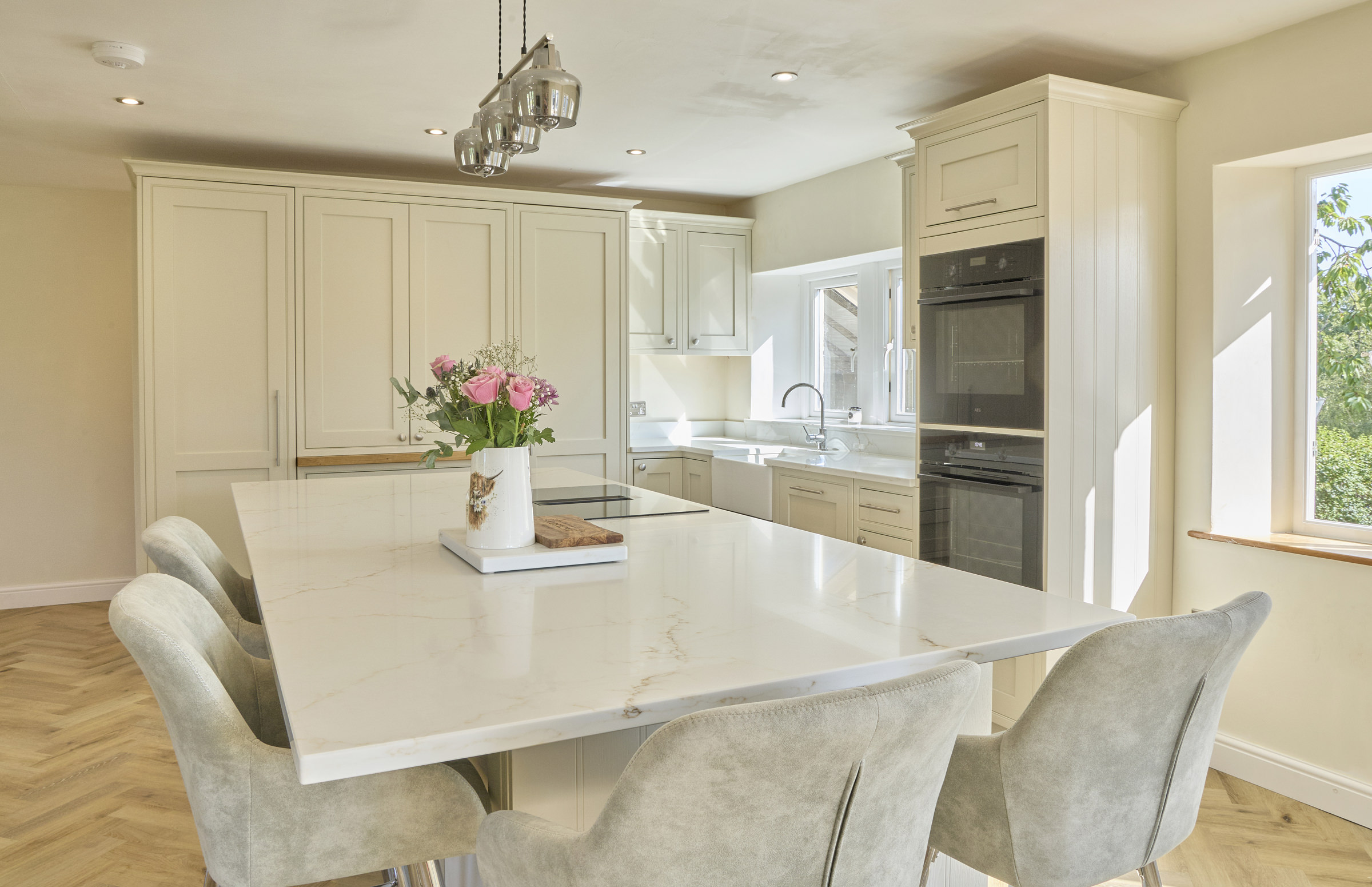A modern kitchen with a silica free statuario oro surface that has a creamy white base and golden-brown veins.